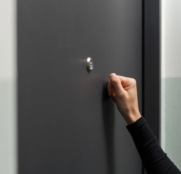 Eine Hand klopft gegen eine schwarze Tür